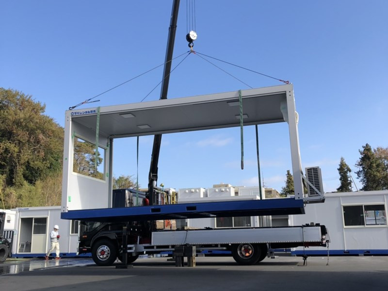 倉庫の横に並んでいるたくさんのトラック